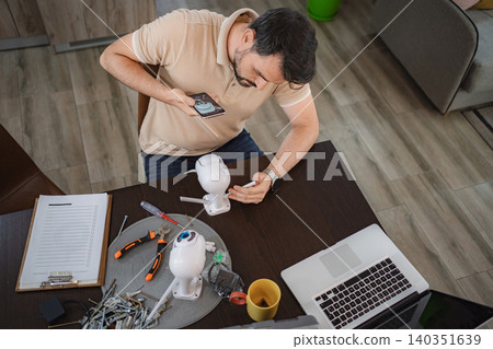 Man installing security camera at home using smartphone app Man installing security camera at home using smartphone app 140351639