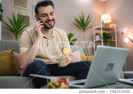 Freelancer enjoying a refreshing drink while working from home 140351640