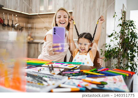 Mother and daughter enjoying a creative art session while taking a selfie at home 140351775