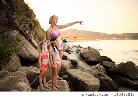 Family on summer vacation pointing out at sunset sea 140351812