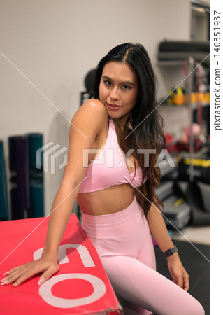 Confident Asian woman in pink activewear looking at camera in gym Confident Asian woman in pink activewear looking at camera in gym 140351937
