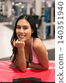 Smiling Asian woman in pink fitness apparel resting on red plyo box in gym 140351940