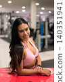 Smiling Asian woman in pink activewear looking away near plyo box in gym 140351941