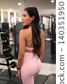 Asian woman in pink activewear looking away in back view portrait in gym 140351950