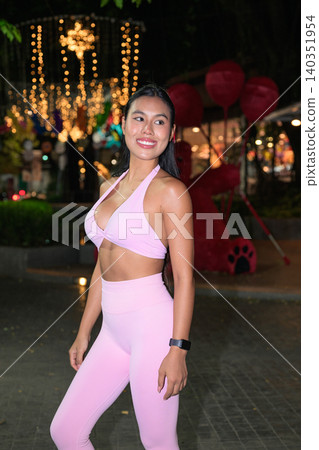Smiling Asian woman in pink sportswear at night street event Smiling Asian woman in pink sportswear at night street event 140351954