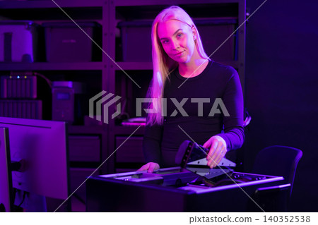 Young white woman upgrades a gaming PC in a purple-lit tech lab, assembling components Young white woman upgrades a gaming PC in a purple-lit tech lab, assembling components 140352538
