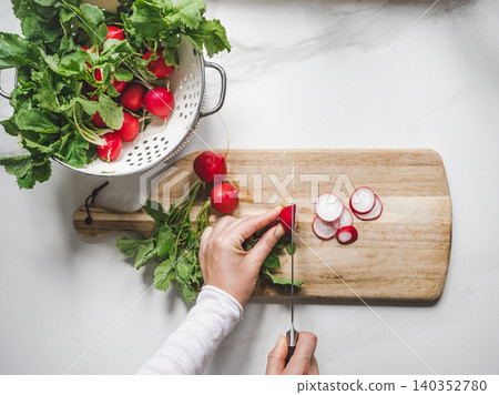 Hands slicing fresh red radishes Hands slicing fresh red radishes 140352780