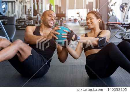 Young black fitness performing medicine ball core exercises together in gym Young black fitness performing medicine ball core exercises together in gym 140352895