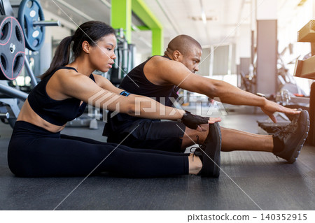 Black fitness stretching together on gym floor before or after workout Black fitness stretching together on gym floor before or after workout 140352915