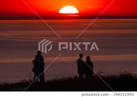People watching sunset over calm ocean with colorful evening sky People watching sunset over calm ocean with colorful evening sky 140352950