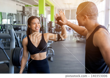 Young black celebrating fitness progress with high five in bright gym Young black celebrating fitness progress with high five in bright gym 140353006