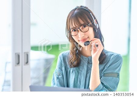 一位戴眼鏡的女客服人員正在調整麥克風。 一位戴眼鏡的女客服人員正在調整麥克風。 140353054