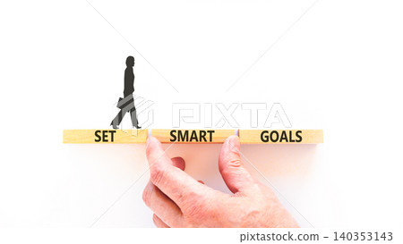 Set smart goals words symbol. Concept words Set smart goals on beautiful wooden blocks. Beautiful white background. Businessman hand. Business and set smart goals concept. Copy space. Set smart goals words symbol. Concept words Set smart goals on beautiful wooden blocks. Beautiful white background. Businessman hand. Business and set smart goals concept. Copy space. 140353143