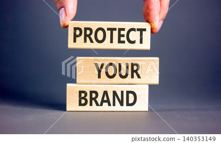 Protect your brand words symbol. Concept words Protect your brand on beautiful wooden blocks. Beautiful grey background. Businessman hand. Business and protect your brand concept. Copy space. Protect your brand words symbol. Concept words Protect your brand on beautiful wooden blocks. Beautiful grey background. Businessman hand. Business and protect your brand concept. Copy space. 140353149