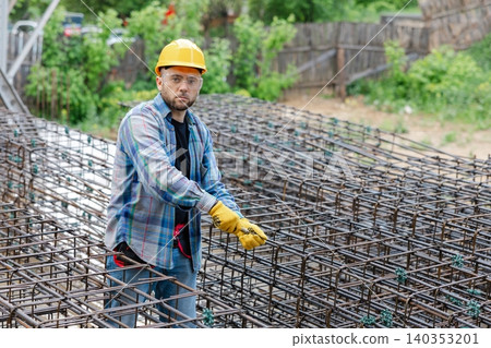 Worker checking reinforcing steel bars at construction site Worker checking reinforcing steel bars at construction site 140353201
