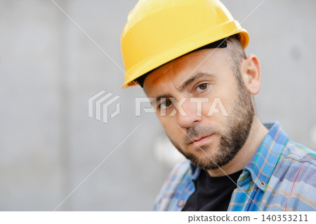 Construction worker wearing hard hat looking down, concentrating Construction worker wearing hard hat looking down, concentrating 140353211