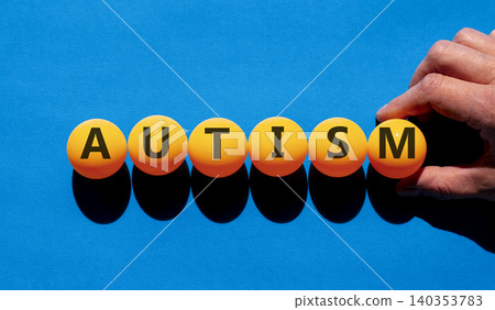 Autism medical symbol. Concept word Autism on beautiful orange table tennis ping pong balls. Beautiful blue background. Doctor's hand. Business autism medical concept. Copy space. Autism medical symbol. Concept word Autism on beautiful orange table tennis ping pong balls. Beautiful blue background. Doctor's hand. Business autism medical concept. Copy space. 140353783