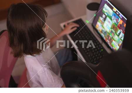 Child uses computer to browse games at home in the afternoon Child uses computer to browse games at home in the afternoon 140353939