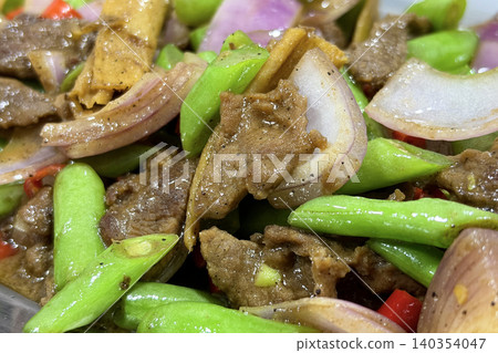 Tender beef slices combined with green stems and vegetables creating a hearty and appetizing cooked meal presentation 140354047