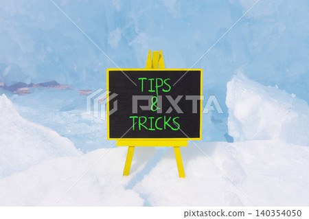 Tips and tricks words symbol. Concept words Tips and tricks on beautiful black blackboard. Beautiful blue ice background. Business tips and tricks motivational support concept. Copy space. 140354050