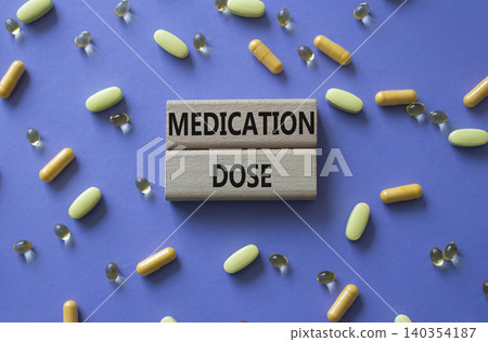Medication dose symbol. Concept word Medication dose on wooden blocks. Beautiful purple background with pills. Medicine and Medication dose. Copy space Medication dose symbol. Concept word Medication dose on wooden blocks. Beautiful purple background with pills. Medicine and Medication dose. Copy space 140354187
