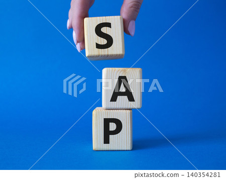 SAP - Systems Applications Products. Wooden cubes with word SAP . Businessman hand. Beautiful blue background. Business and System Application Product concept. Copy space. 140354281