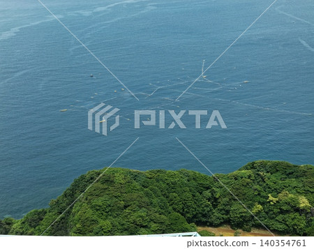 Aerial photograph capturing aquaculture pens and coastal forest off the coast of Tateura, Ikitsuki Island, Nagasaki Prefecture. Aerial photograph capturing aquaculture pens and coastal forest off the coast of Tateura, Ikitsuki Island, Nagasaki Prefecture. 140354761