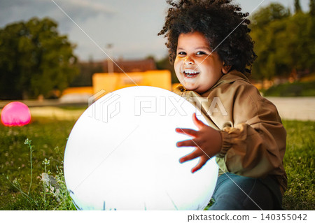 Child playing with glowing ball in park at dusk Child playing with glowing ball in park at dusk 140355042