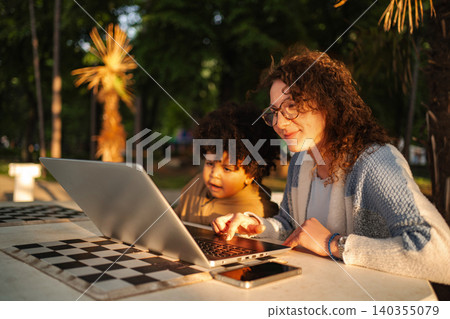 Woman and child learning outdoors using laptop together Woman and child learning outdoors using laptop together 140355079
