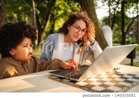 Mother and child learning together using laptop in park Mother and child learning together using laptop in park 140355081