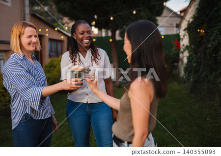 Diverse women friends celebrating with drinks in backyard party Diverse women friends celebrating with drinks in backyard party 140355093