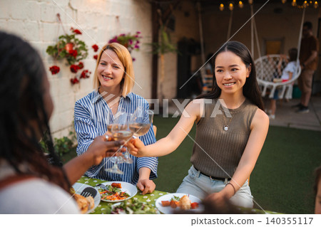Multi ethnic women friends toasting with wine outdoor Multi ethnic women friends toasting with wine outdoor 140355117
