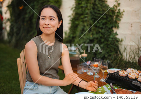 Young Asian woman enjoying outdoor barbecue dinner party Young Asian woman enjoying outdoor barbecue dinner party 140355119