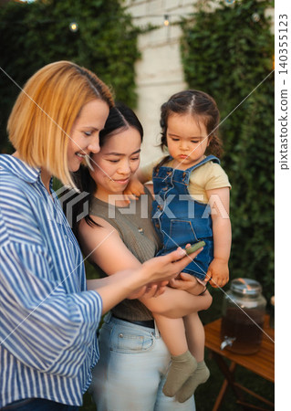 Diverse family watching smartphone content during outdoor gathering Diverse family watching smartphone content during outdoor gathering 140355123