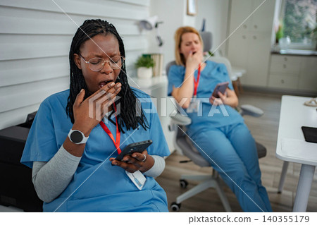 Tired medical workers yawning during long shift break Tired medical workers yawning during long shift break 140355179