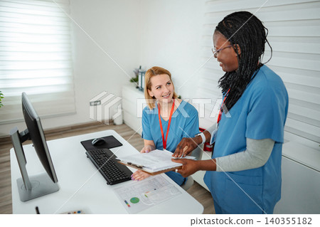 Nurses discussing patient files in hospital office 140355182