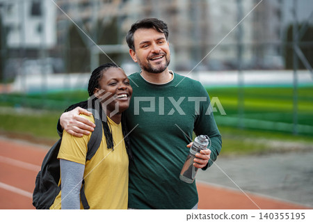 Man and woman enjoying a workout, smiling and laughing on a running track 140355195