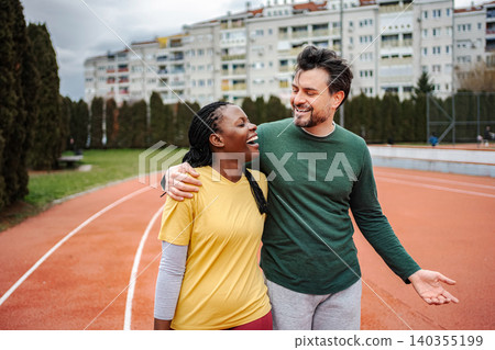 Diverse couple laughing and talking on a running track 140355199
