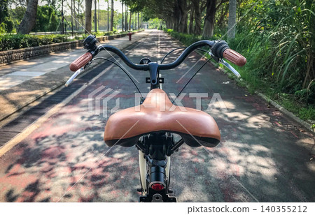 Vintage bicycle saddle and handlebars on a scenic park path Vintage bicycle saddle and handlebars on a scenic park path 140355212