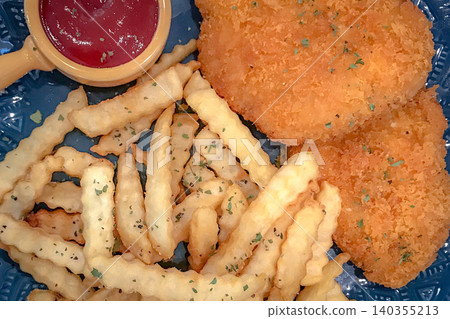 Crispy fried chicken tenders with crinkle cut fries and ketchup on a blue plate Crispy fried chicken tenders with crinkle cut fries and ketchup on a blue plate 140355213