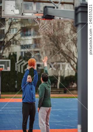 Two male adults playing basketball on outdoor court Two male adults playing basketball on outdoor court 140355221
