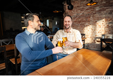 Two men toasting with beer cheering in a bar 140355228