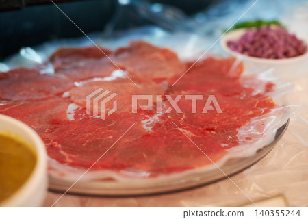 Carpaccio, closeup and food on plate for dinner with appetizer, fine dining and buffet of raw meat in restaurant. Beef, seafood and protein meal on table for nutrition, snack or lunch at social event Carpaccio, closeup and food on plate for dinner with appetizer, fine dining and buffet of raw meat in restaurant. Beef, seafood and protein meal on table for nutrition, snack or lunch at social event 140355244
