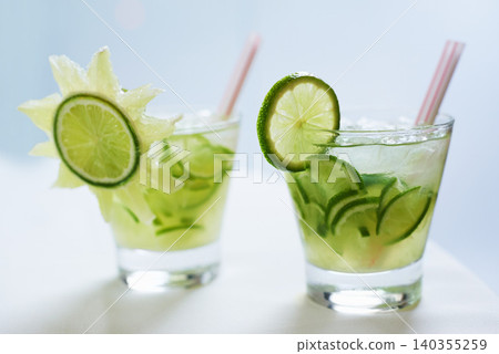 Cocktail, alcohol and mojito with lime for drink on table for party, club and bar or restaurant. Glass, background and closeup of mocktail, beverage and liquid with fruit, ice and liquor for drinking Cocktail, alcohol and mojito with lime for drink on table for party, club and bar or restaurant. Glass, background and closeup of mocktail, beverage and liquid with fruit, ice and liquor for drinking 140355259