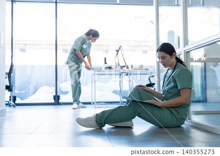 Doctor in a lab coat sitting on the floor and reading medical history of the patient Doctor in a lab coat sitting on the floor and reading medical history of the patient 140355273