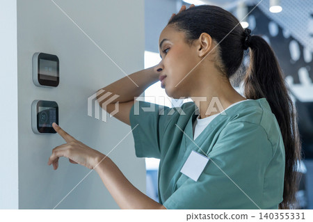 Tired after night shift doctor setting temperature on a climate control panel 140355331