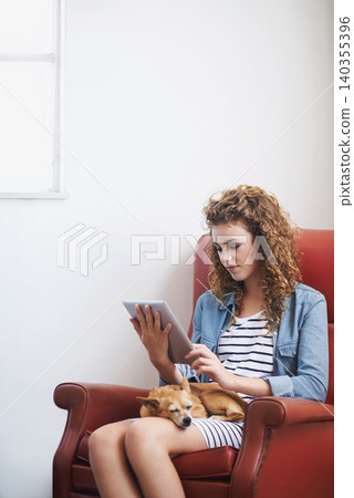 Woman, tablet and relax on social media at home, online and internet for website or blogging. Female person, dog and streaming entertainment on armchair, pet animal and app for shopping on weekend Woman, tablet and relax on social media at home, online and internet for website or blogging. Female person, dog and streaming entertainment on armchair, pet animal and app for shopping on weekend 140355396
