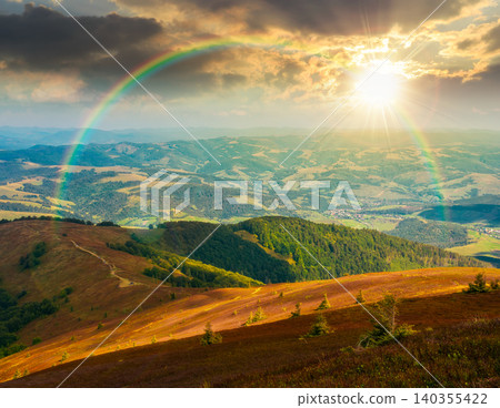 sunset over mountainous countryside scenery. view of cloudy sky above the valley. colorful meadows and trees on hill in dappled light. beautiful nature scenery of carpathians. weather with rainbow sunset over mountainous countryside scenery. view of cloudy sky above the valley. colorful meadows and trees on hill in dappled light. beautiful nature scenery of carpathians. weather with rainbow 140355422
