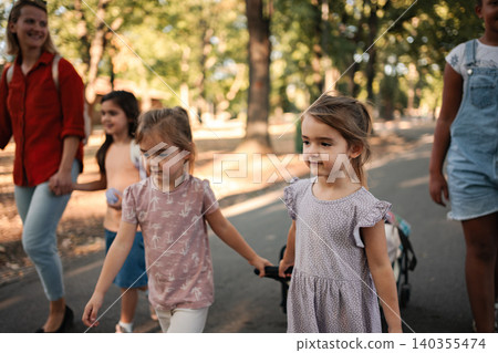 Little girls walking in the park with their teacher and classmates 140355474