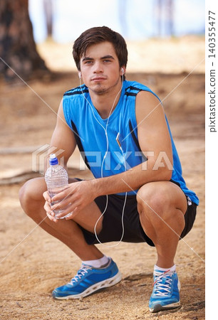 Portrait, water or runner on break with earphones in outdoor exercise or fitness workout for podcast. Man, ready or male athlete listening to playlist for streaming radio, music or sports training Portrait, water or runner on break with earphones in outdoor exercise or fitness workout for podcast. Man, ready or male athlete listening to playlist for streaming radio, music or sports training 140355477